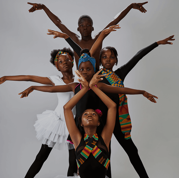Children and young adults in colorful traditional attire performing dance moves